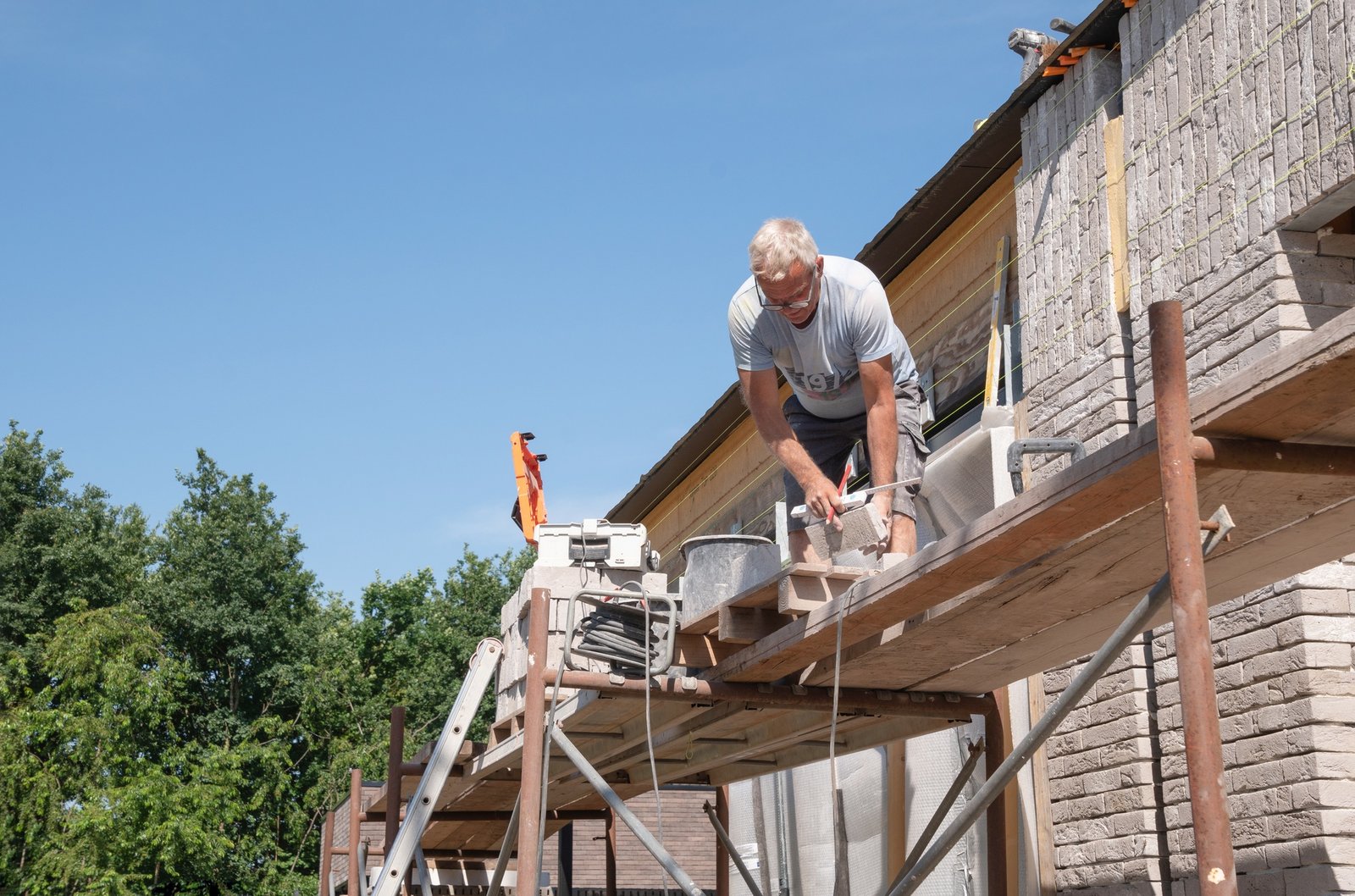 masonry worker the bricklayer makes the facade of the house from gray bricks